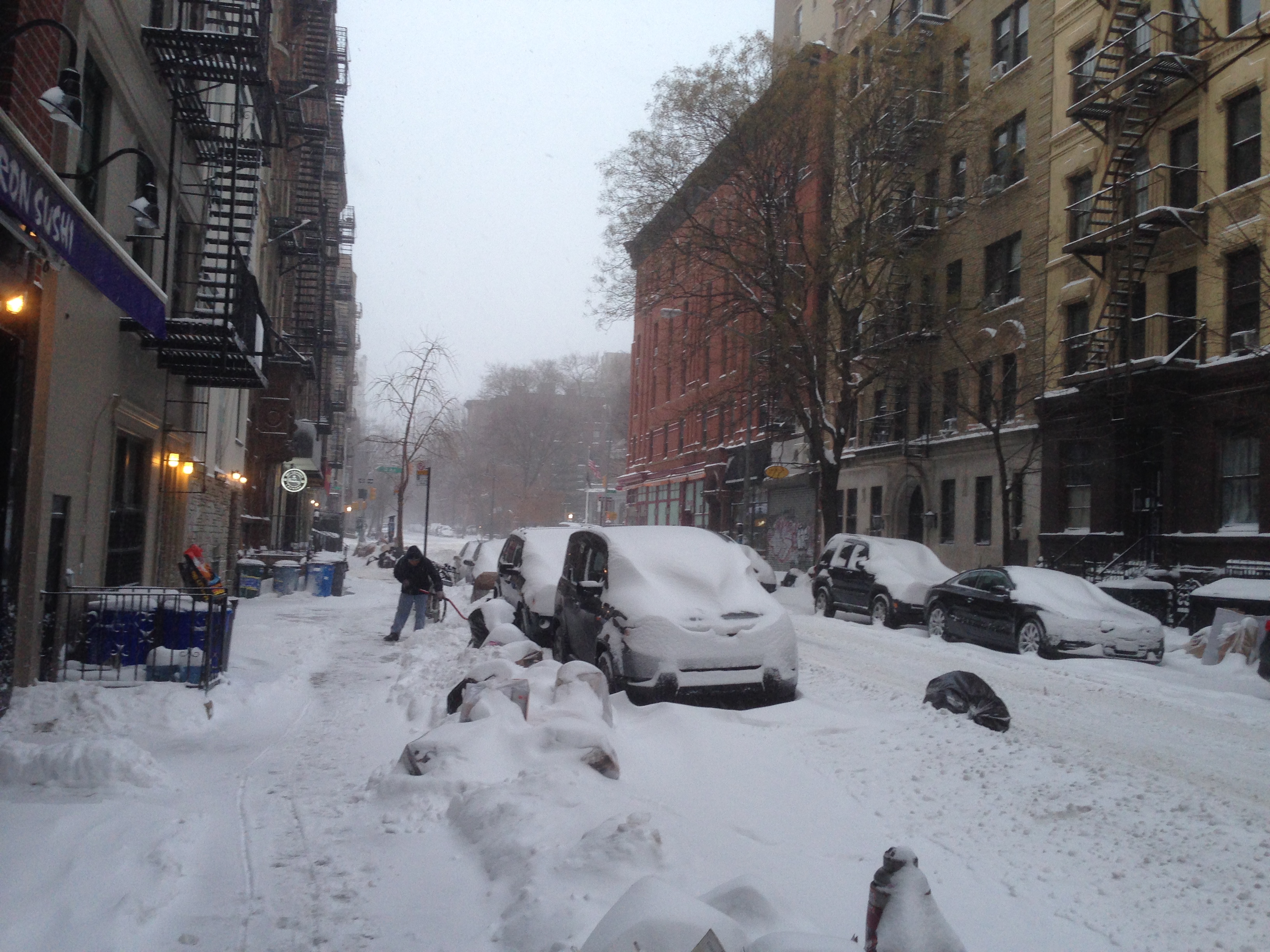 Snow-covered city street with buried cars