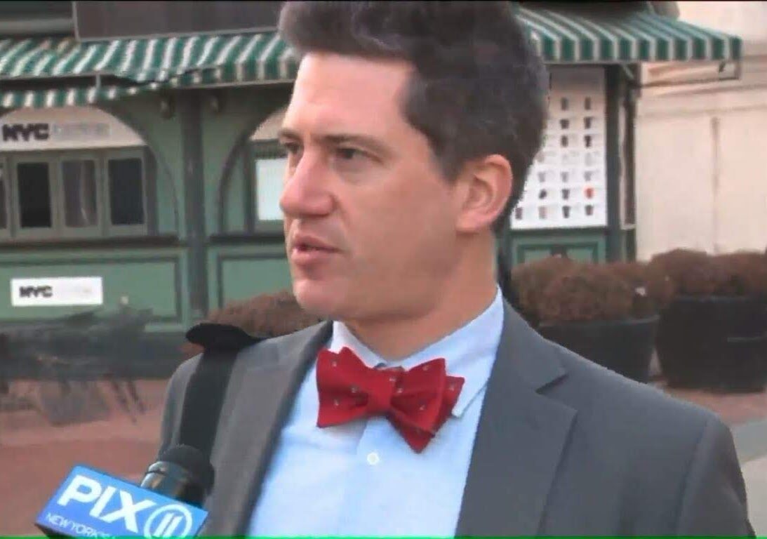 Man in suit with red bow tie interviewed